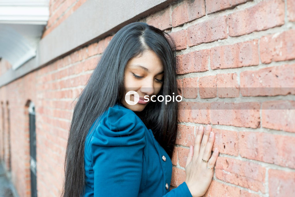 Woman leaning her head on brick wall closing her eyes