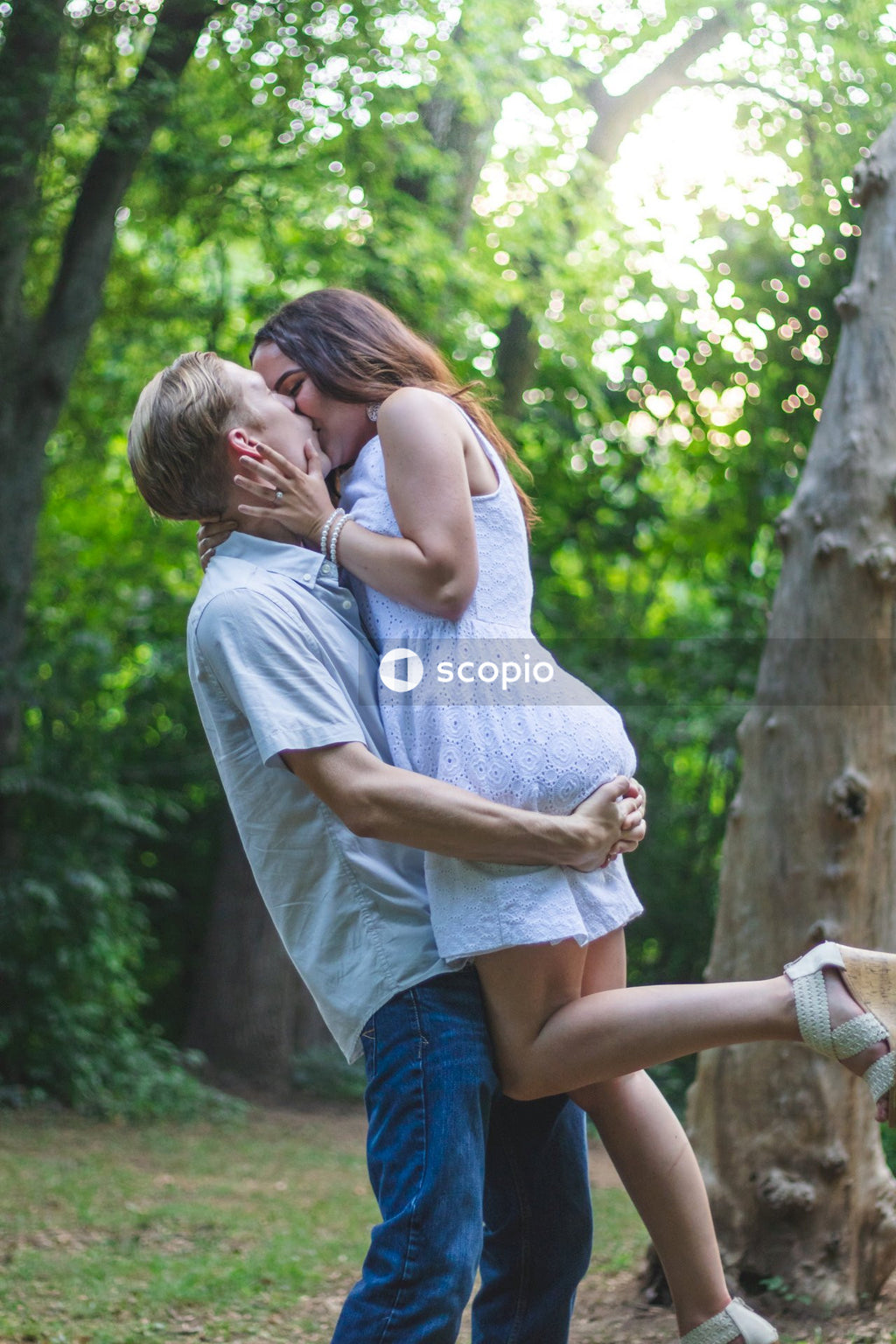 Man in white shirt and blue denim shorts carrying a woman