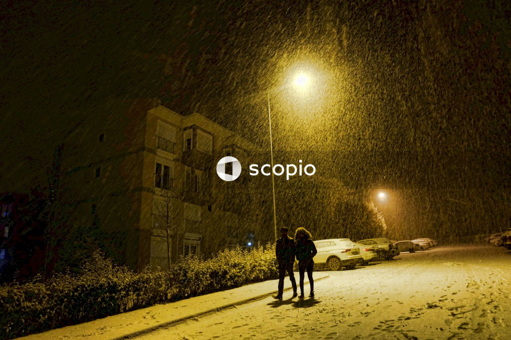 Silhouette of man and woman walking on the road during snowy night