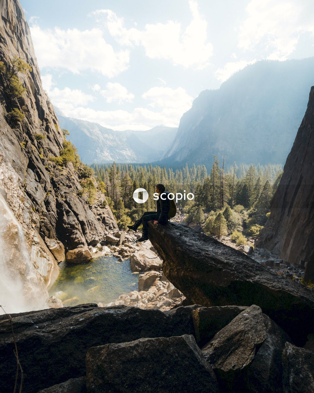 Person sitting on brown rock near river
