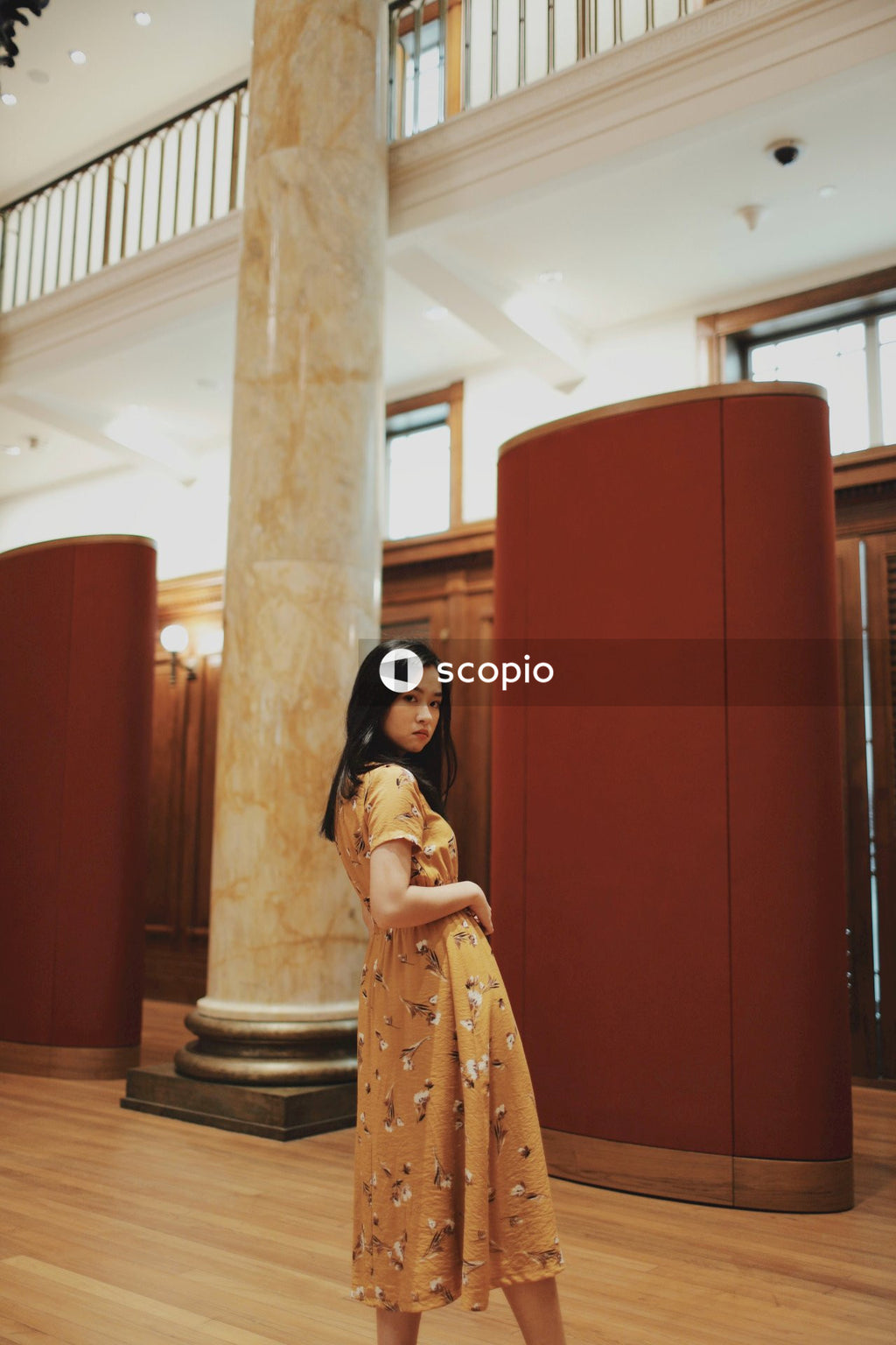 Woman in long orange dress sitting on big hall