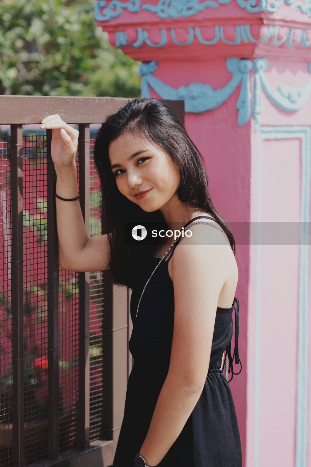 Woman in Dark Dress Standing Near Dark Fence