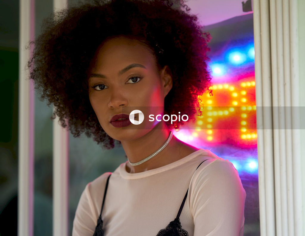 Woman in white top standing next to neon sign