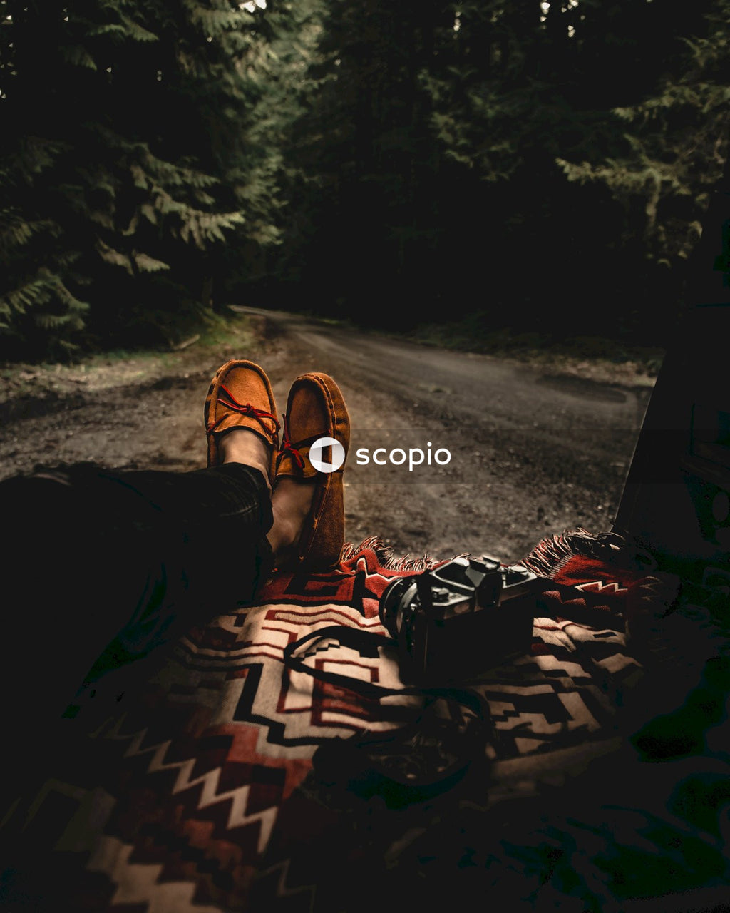 Person in black pants and brown hiking shoes lying on black and white textile