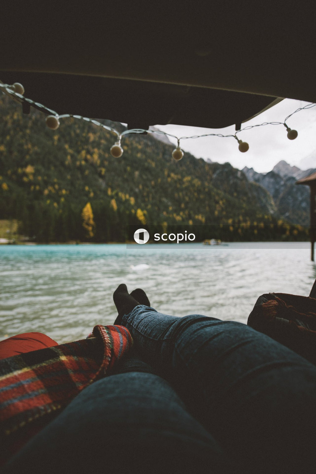 Person in blue denim jeans sitting in a tent near lake