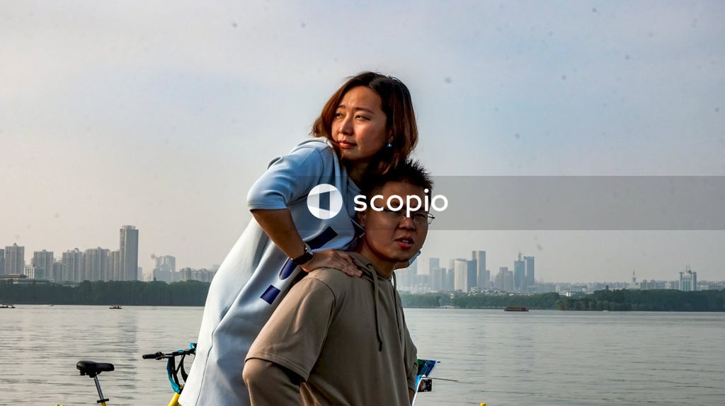Man in white polo shirt hugging woman in brown coat