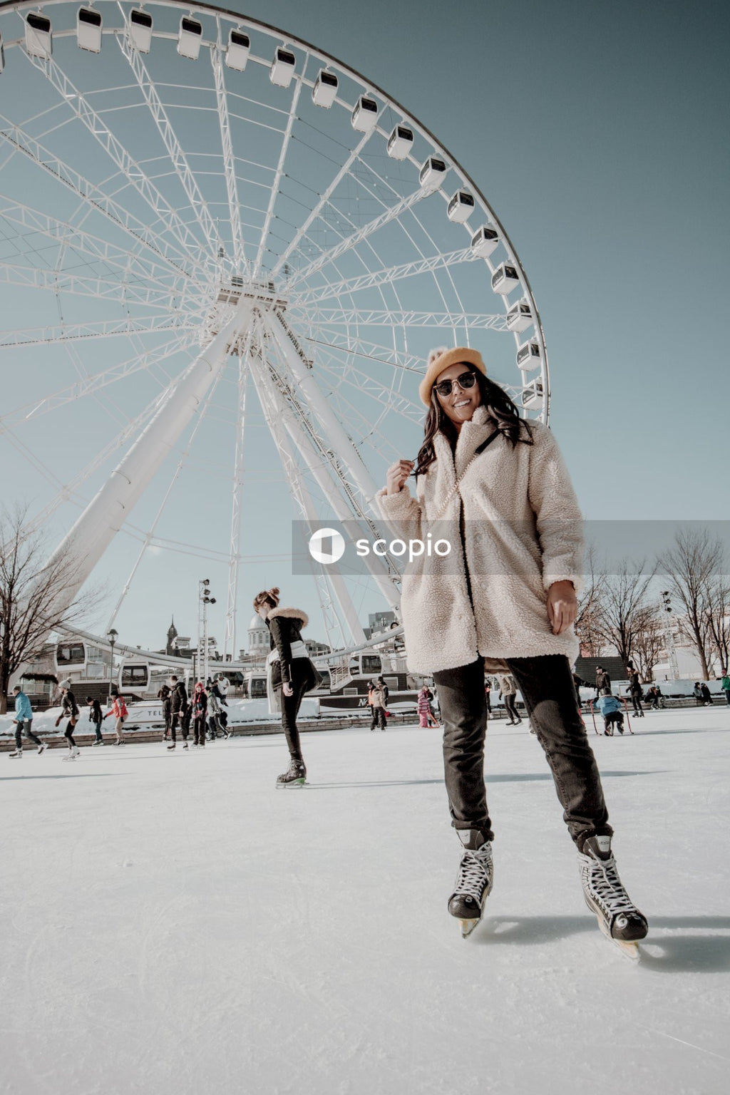 Smiling woman wearing white jacket standing on ice near ferris wheel