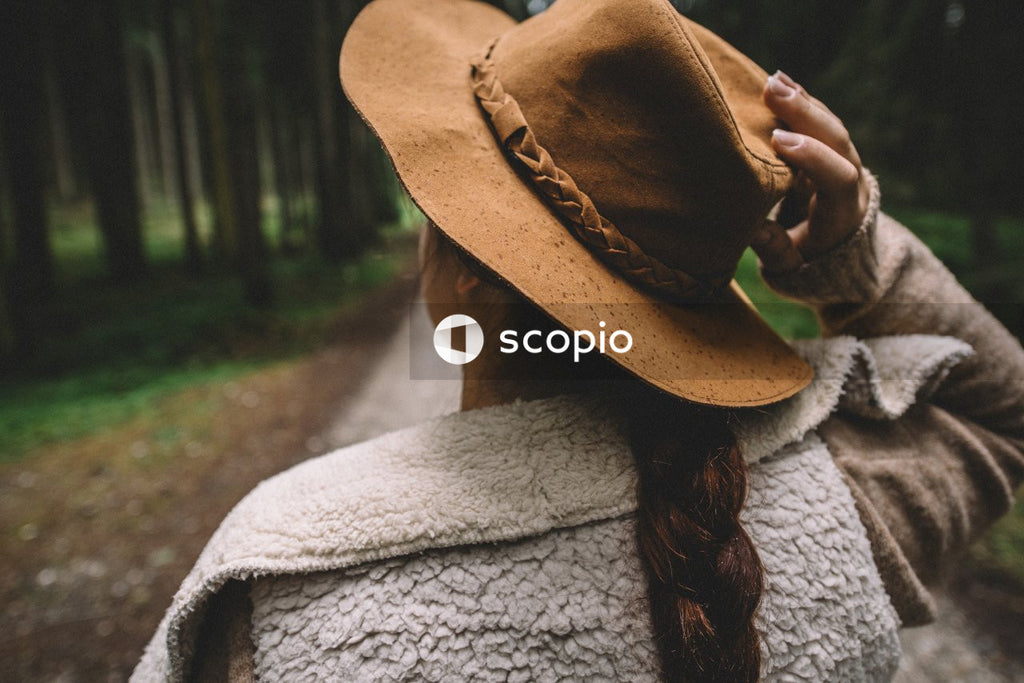 Back view of woman with braided hair wearing a hat standing in the woods