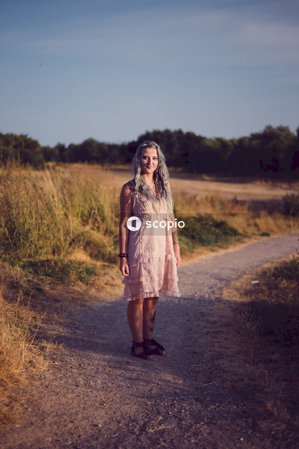 Woman in brown dress standing on dirt road