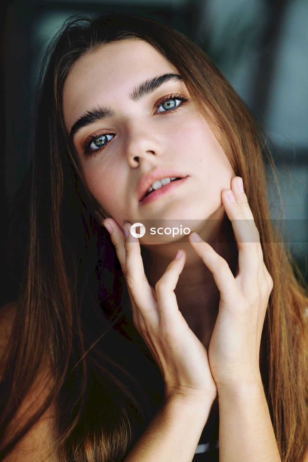 Woman with brown hair touching her face