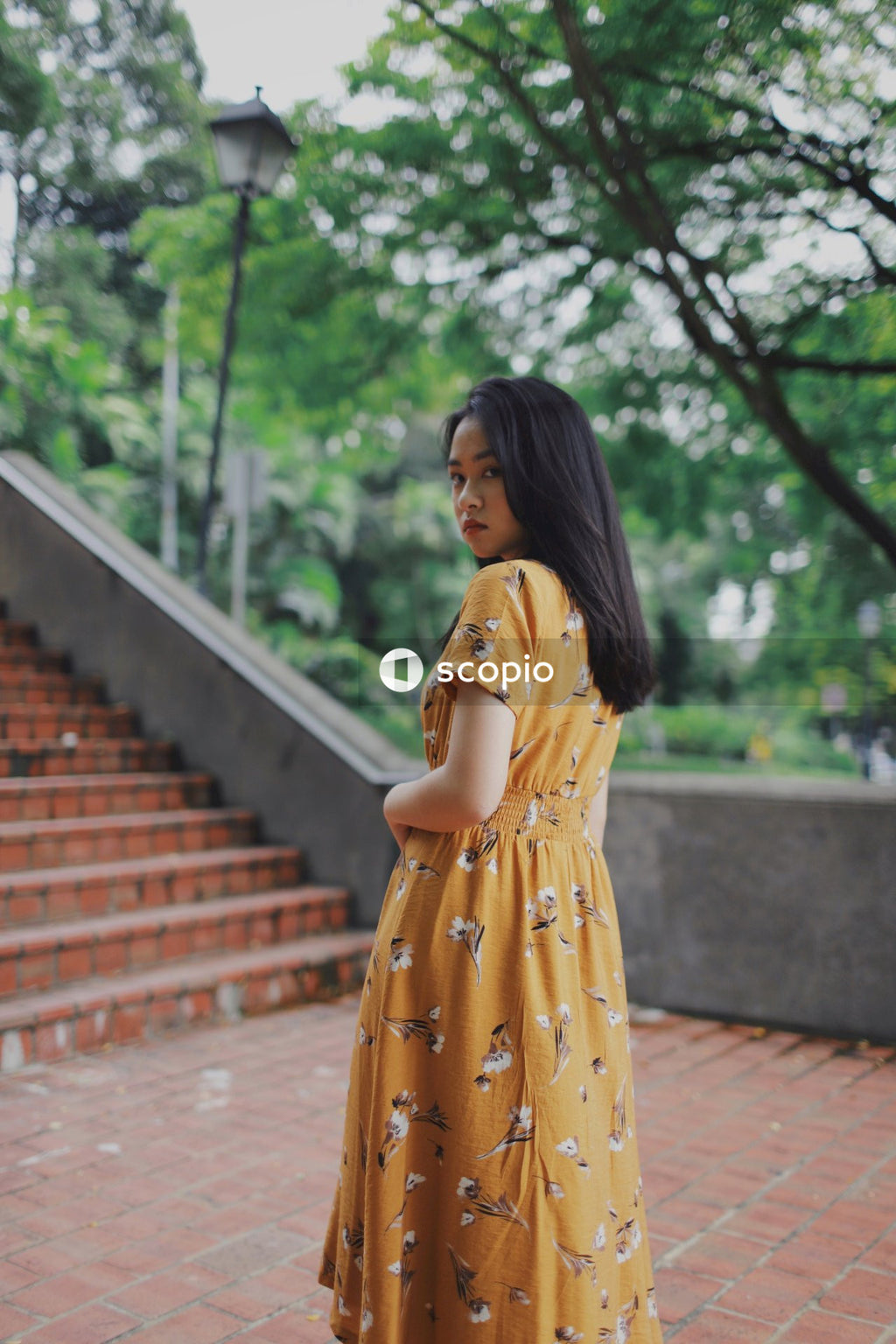 Asian woman in orange dress standing on stairs