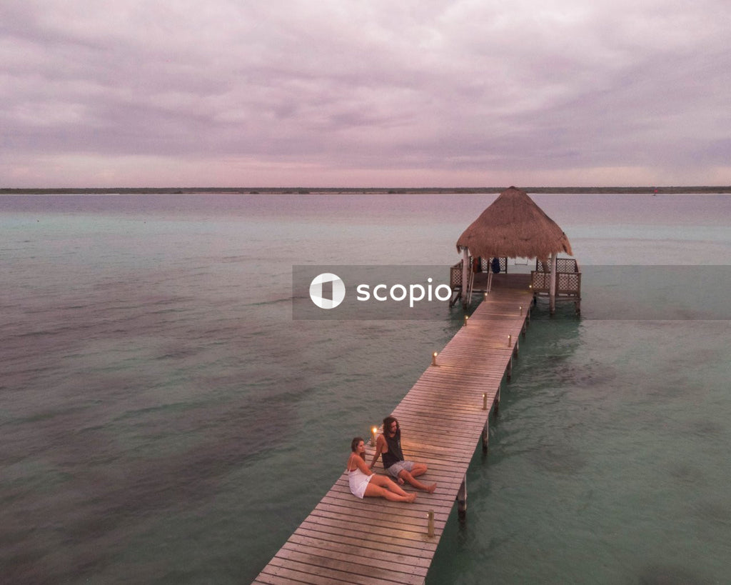 Man an woman sitting on wooden dock above water