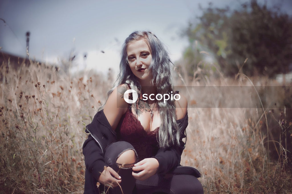 Woman in black jacket sitting on brown grass field