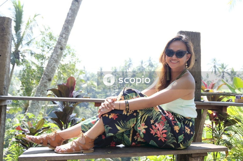 Woman in white and black floral dress sitting on brown wooden bench