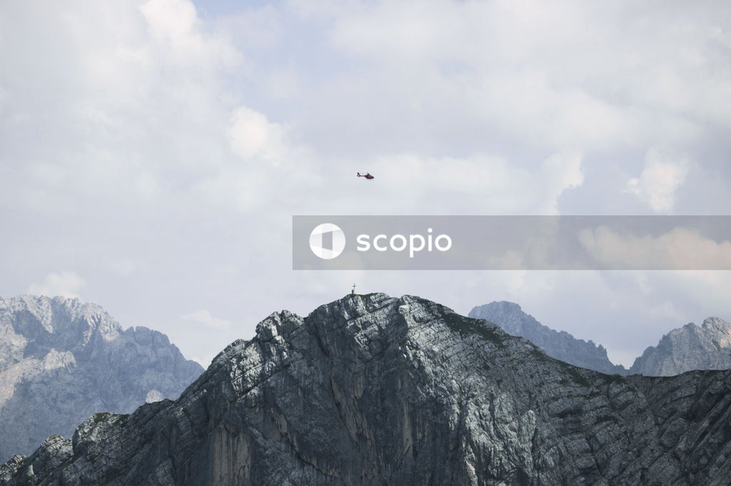 Red and white plane flying over mountain