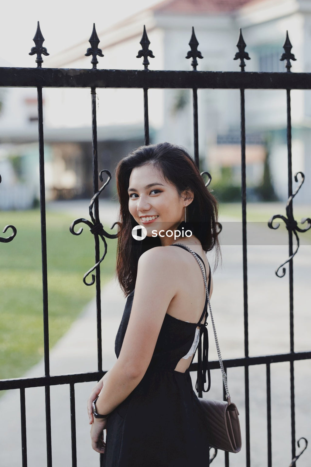 Woman in dark dress standing near dark fence