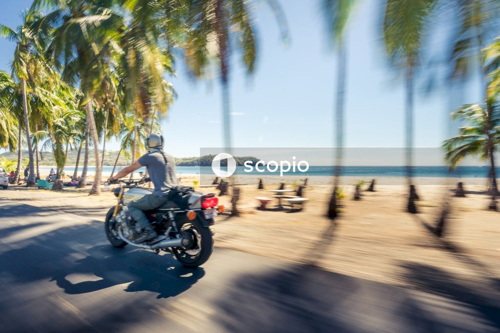 Man in gray shirt riding motorcycle on beach