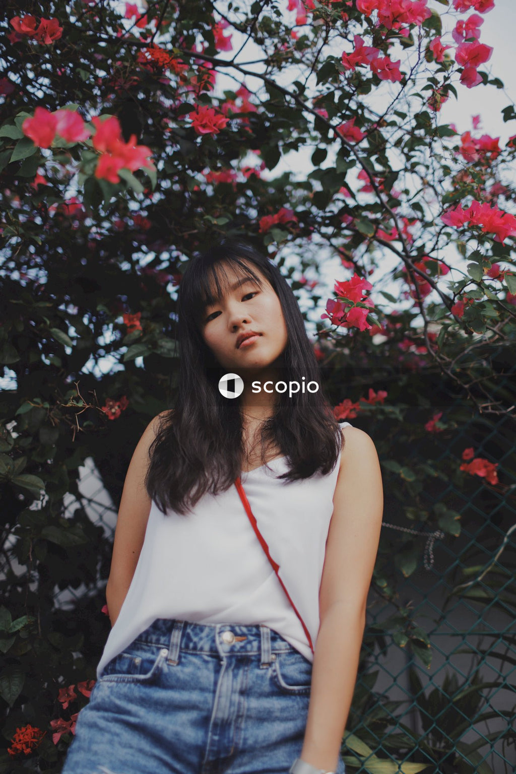 Woman with bangs posing near flowers and bushes