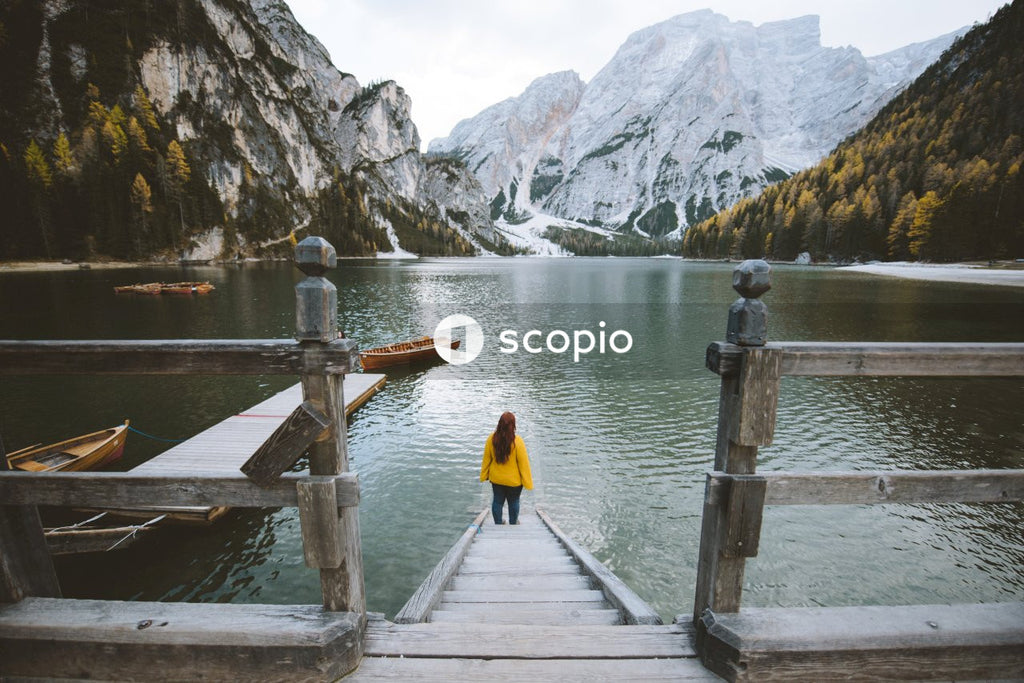 Person in yellow jacket and black pants standing on wooden dock