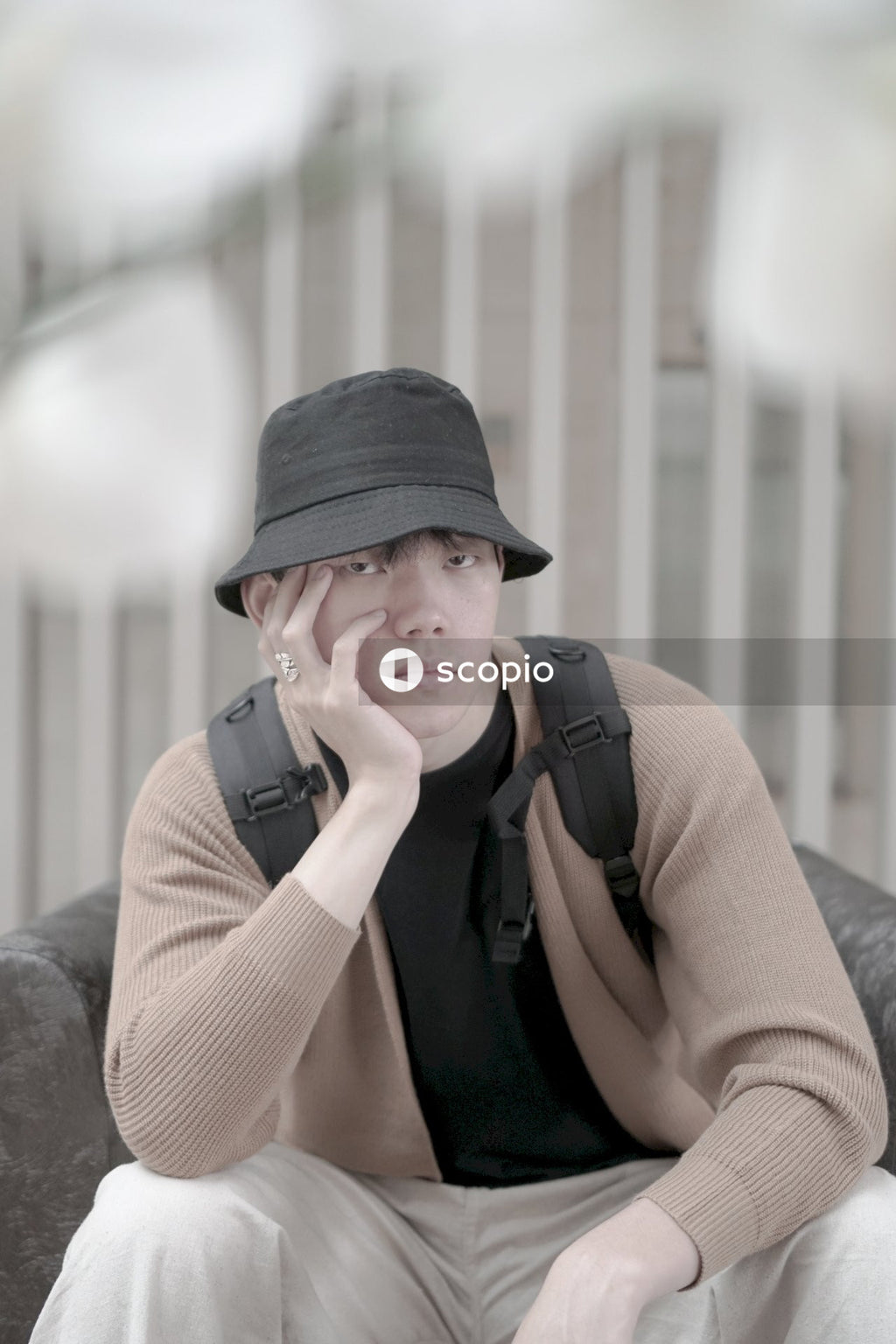 Portrait of man with black hat and backpack sitting indoors
