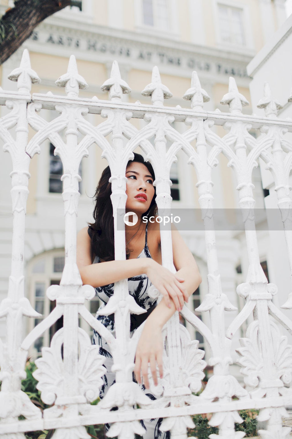Woman in light and dark jumpsuit behind light building fence