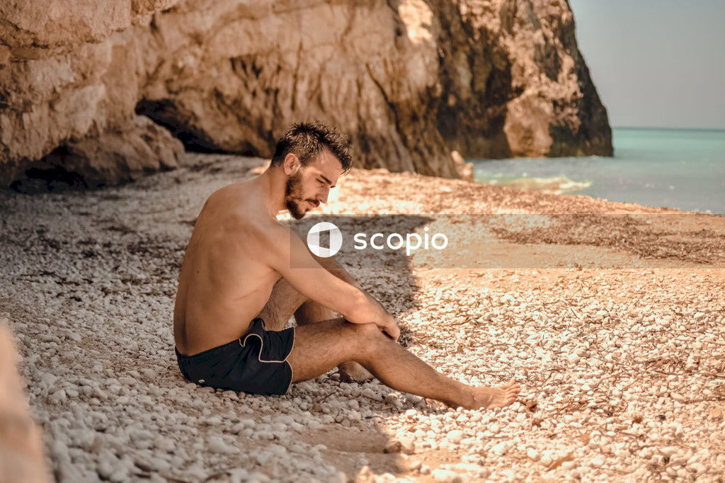 Man in shorts sitting on brown sand