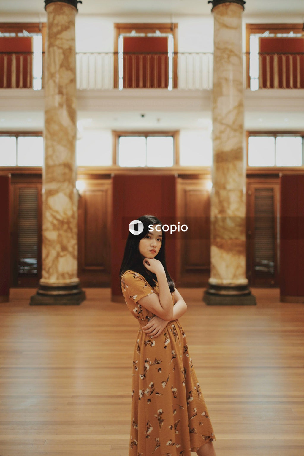 Woman in long orange dress sitting on big hall