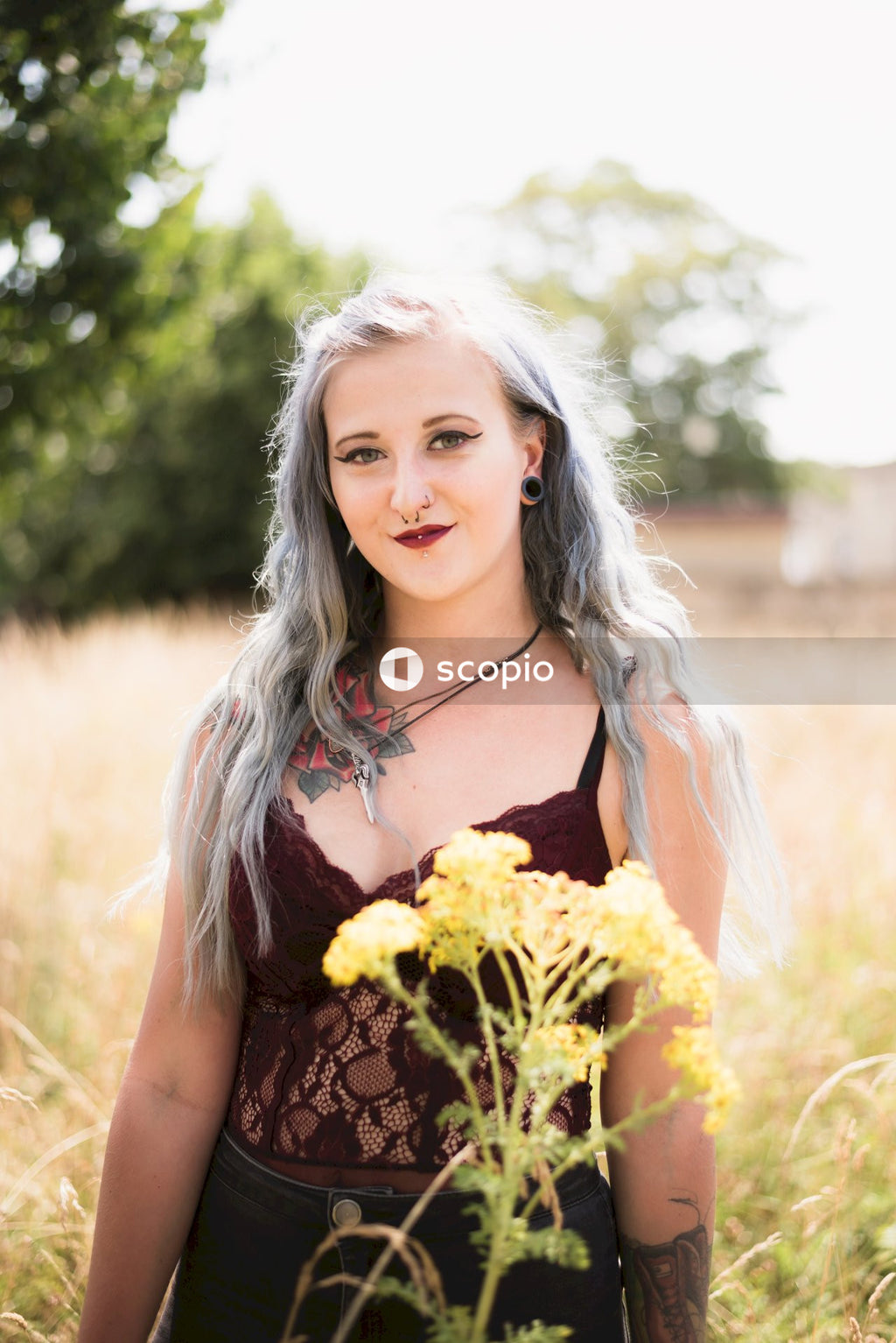 Woman in black and yellow floral spaghetti strap top holding yellow flowers