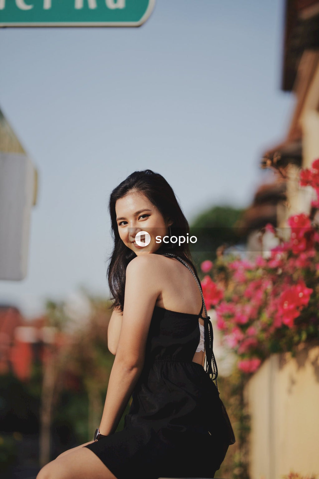 Woman in dark dress posing near flowers bushes