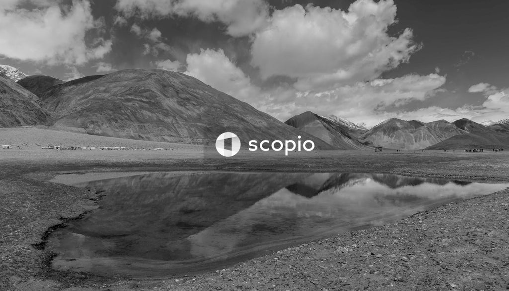 Grayscale photo of mountain under cloudy sky