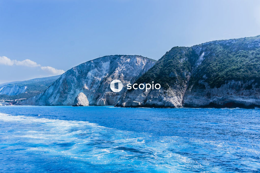 Green and brown mountain beside blue sea under blue sky