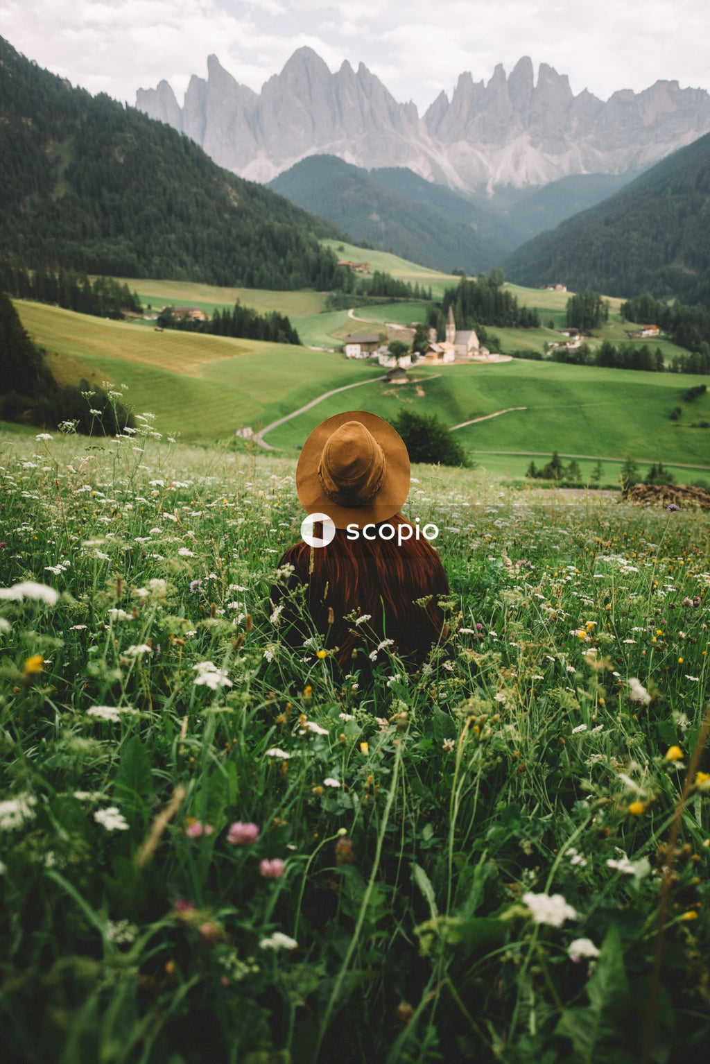 Woman in brown hat sitting on white flower field