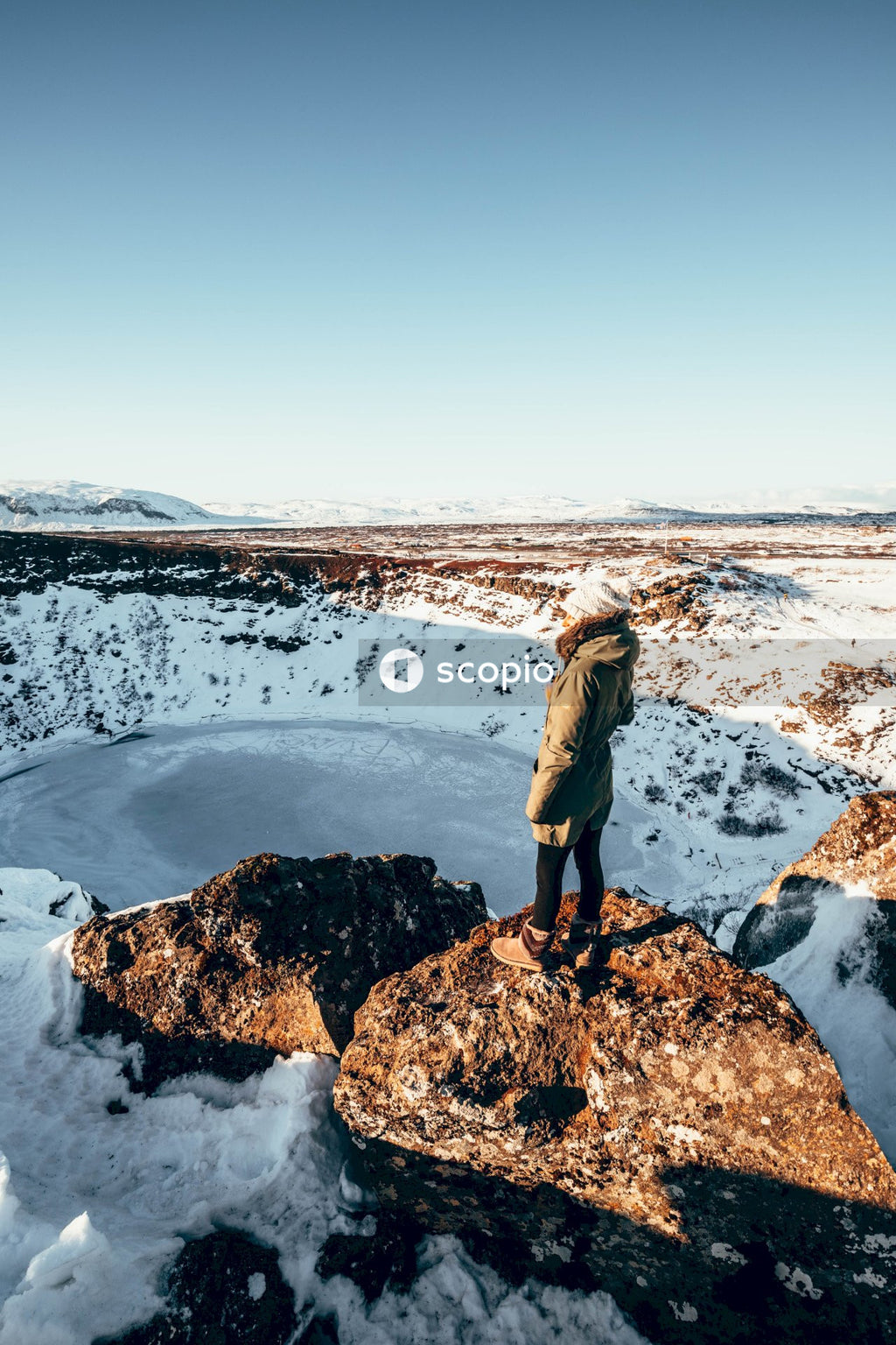 Woman standing on rock formation near body of water