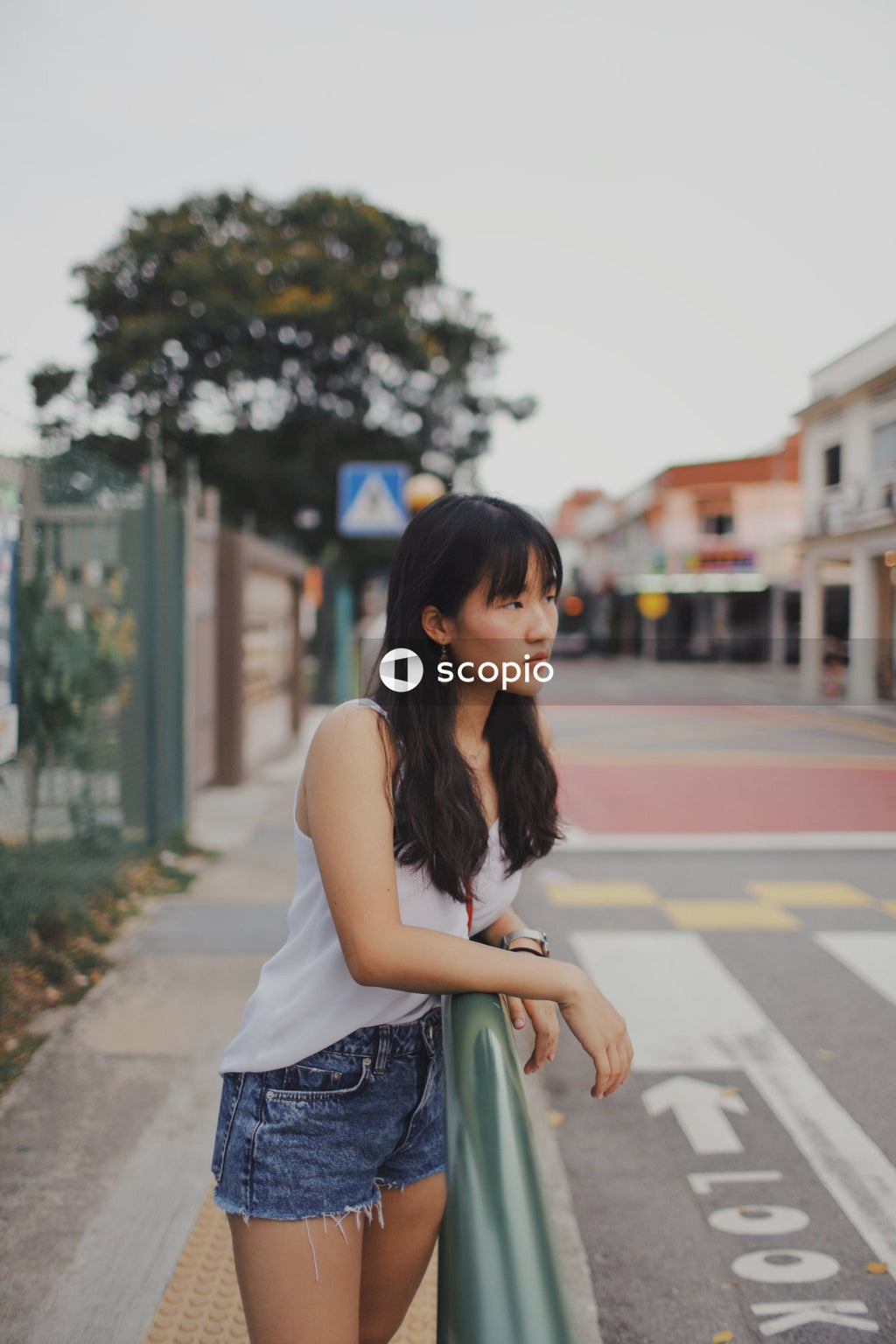 Young woman with bangs wearing light top and short standing on the street