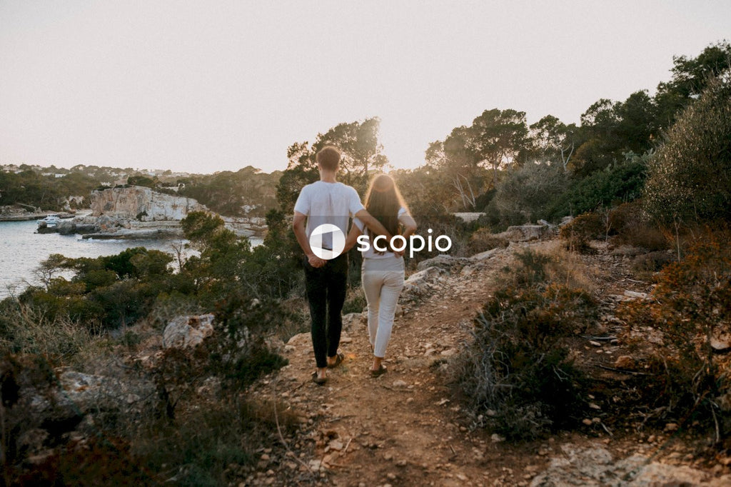 Man and woman holding hands while walking on dirt road