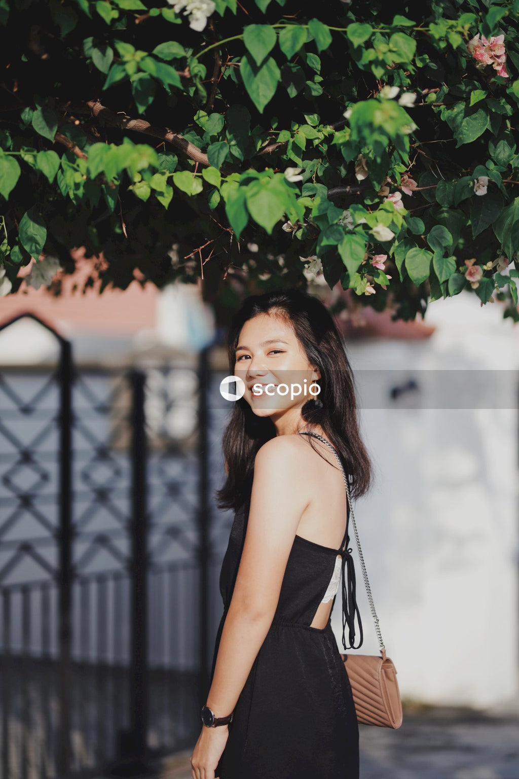 Woman in dark dress standing near dark fence