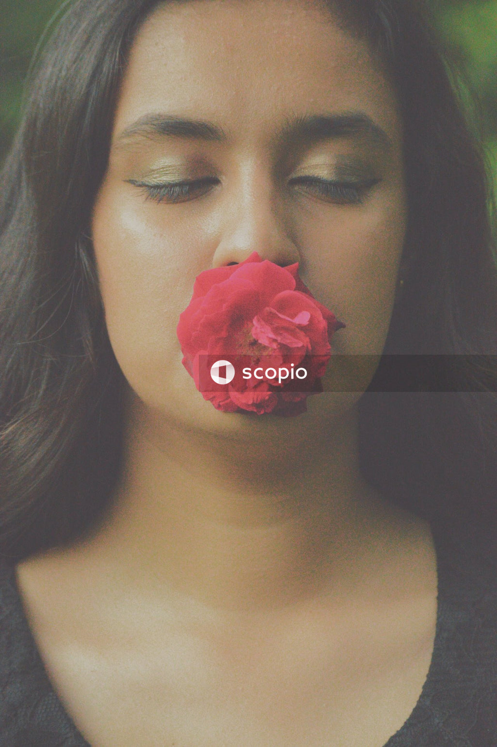 Woman holding red rose with her mouth