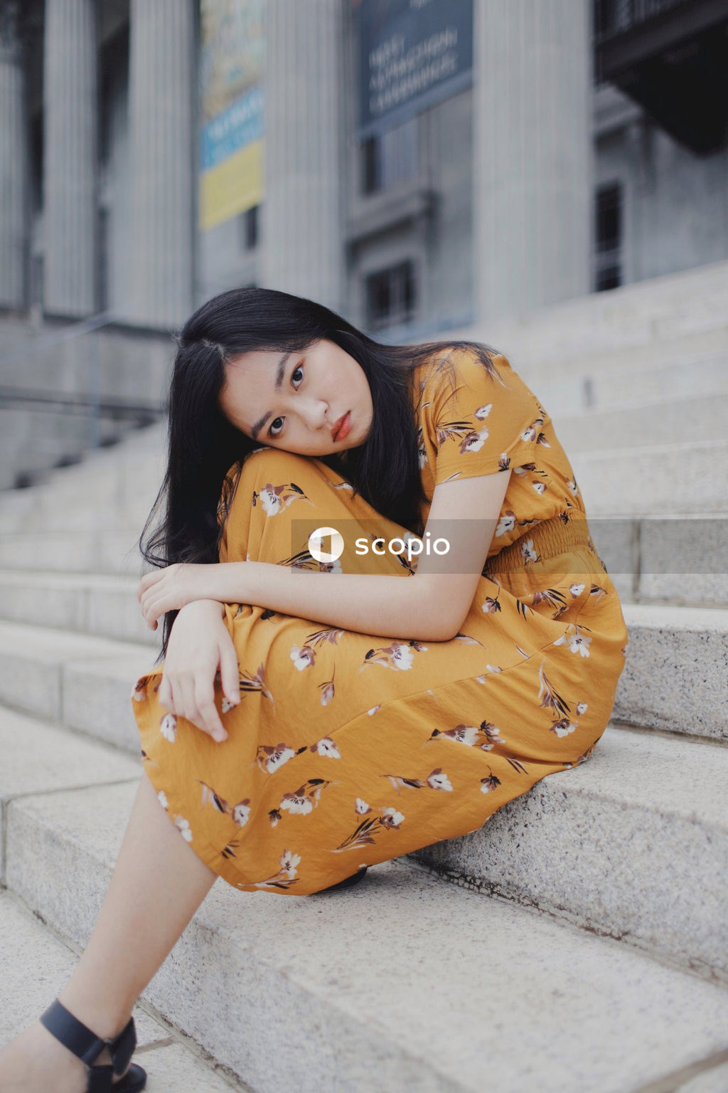 Girl in orange dress sitting on concrete stairs