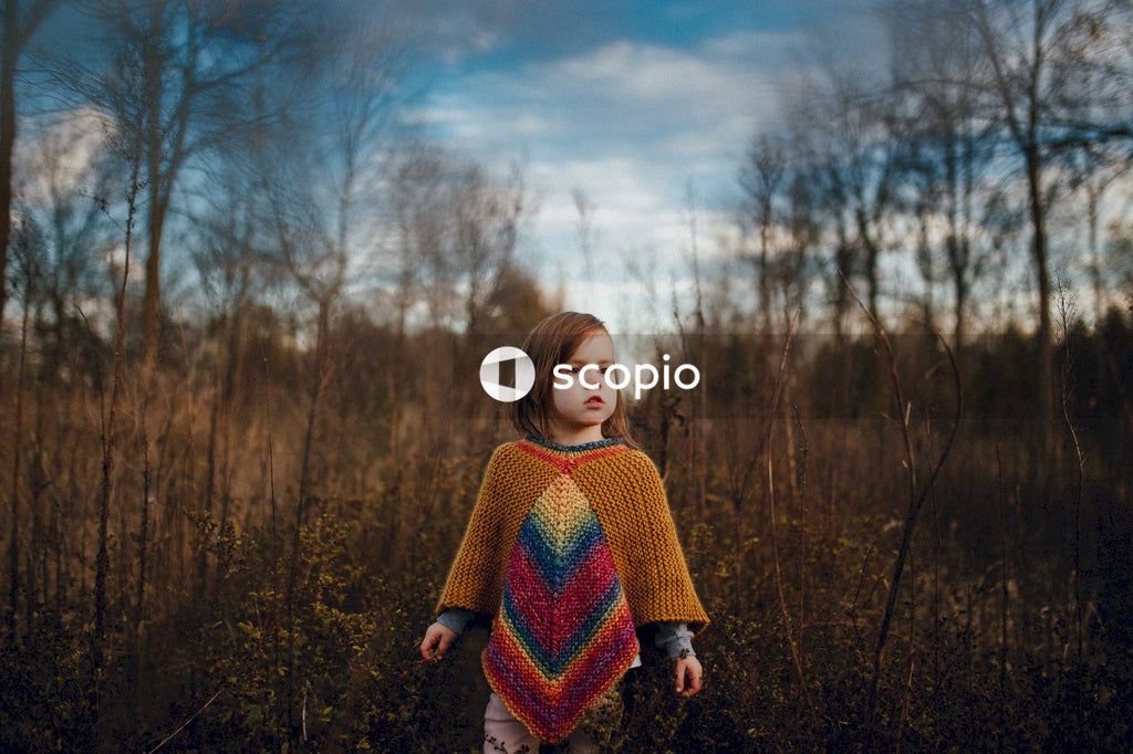 Young girl in sweater standing in dry grass field