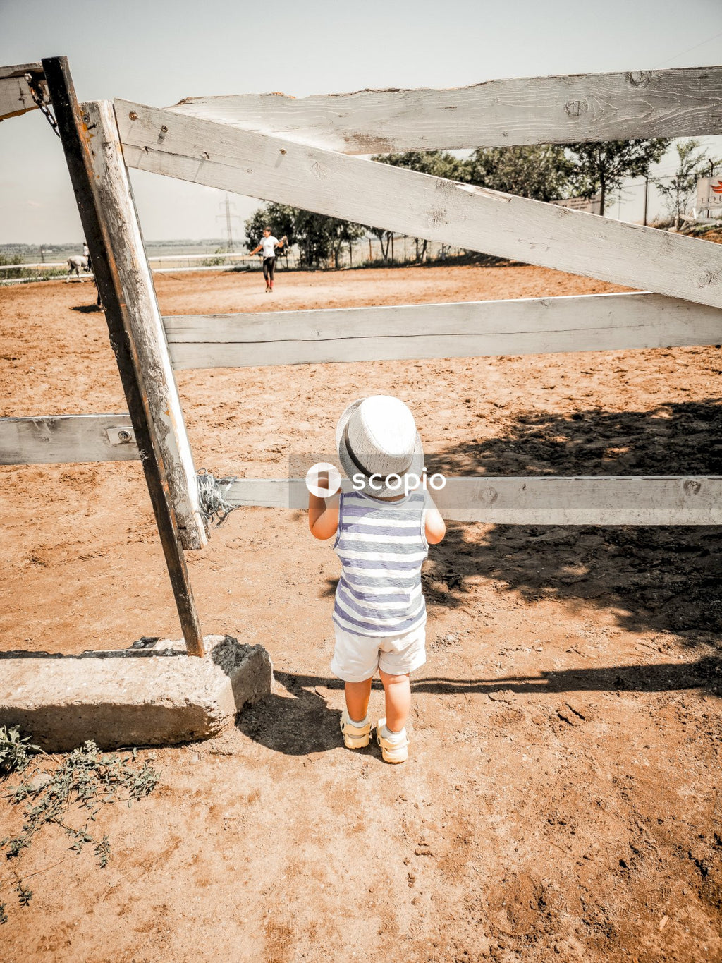 Child standing while holding wooden fence