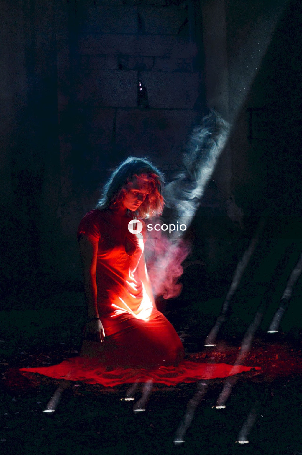 Woman kneeling on mat under red spotlight in dark space