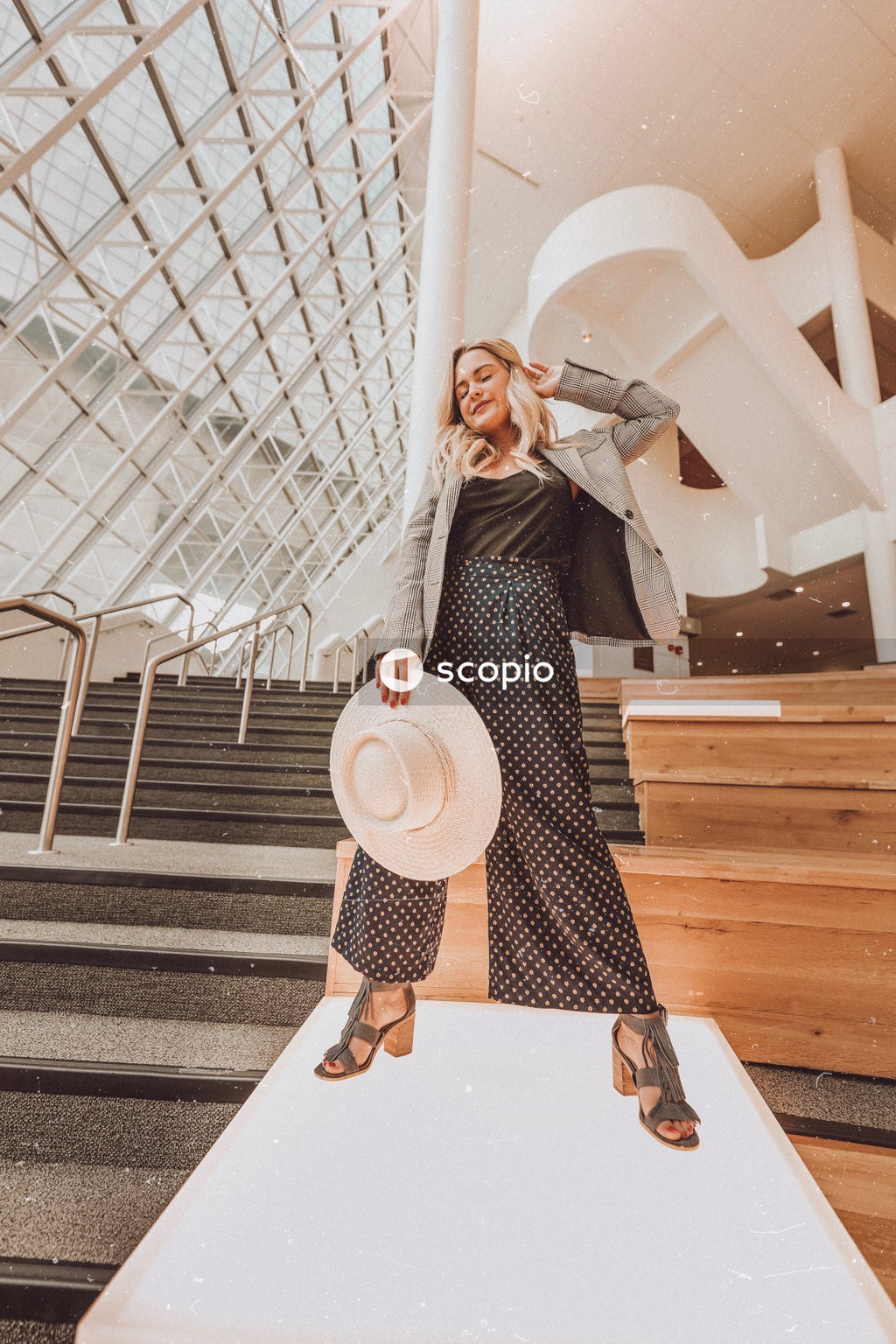 Woman in black and white long sleeve dress wearing brown hat standing on white wooden stairs