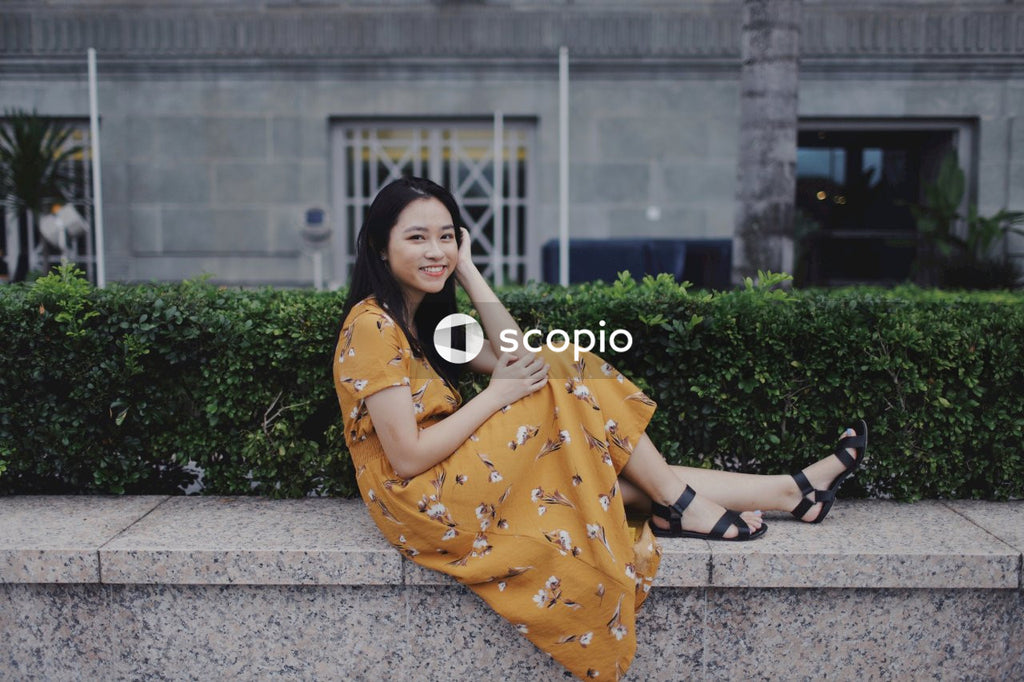 Woman in long orange dress sitting on concrete bench