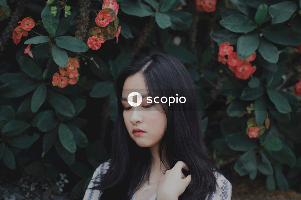 East Asian woman sitting in front of flowers with closed eyes