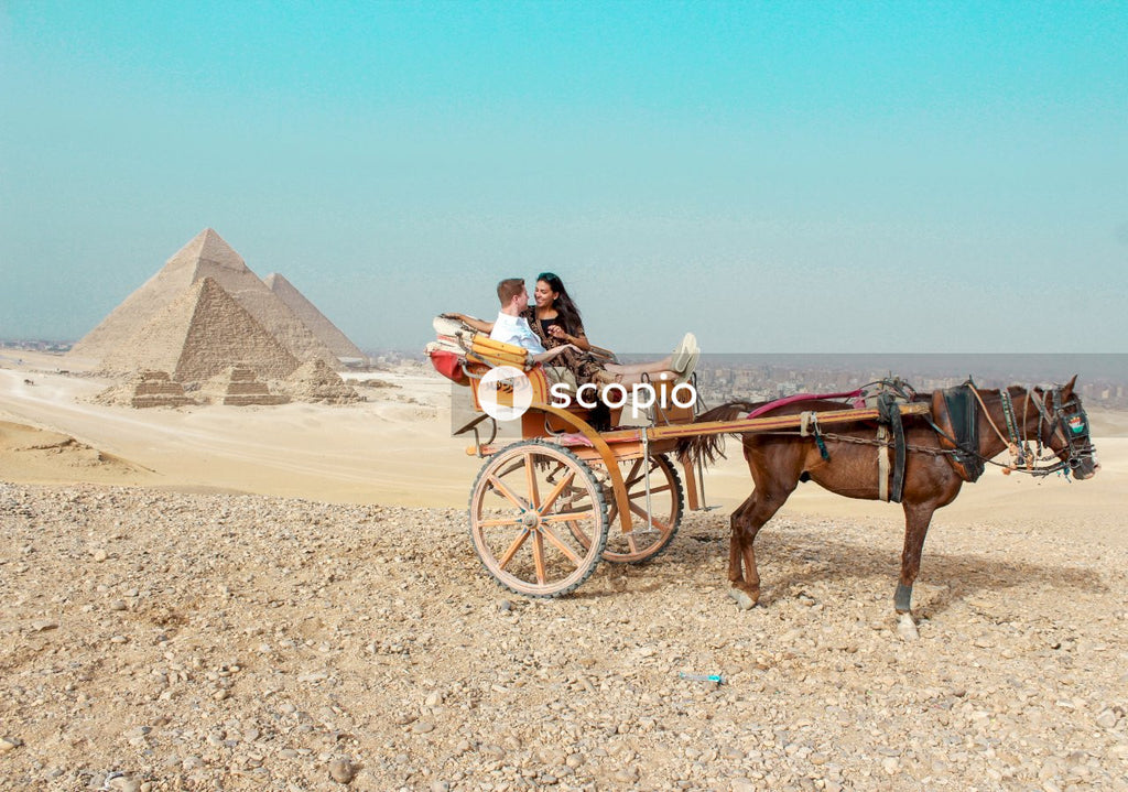 Couple enjoying horse carriage ride in desert near pyramids, egypt