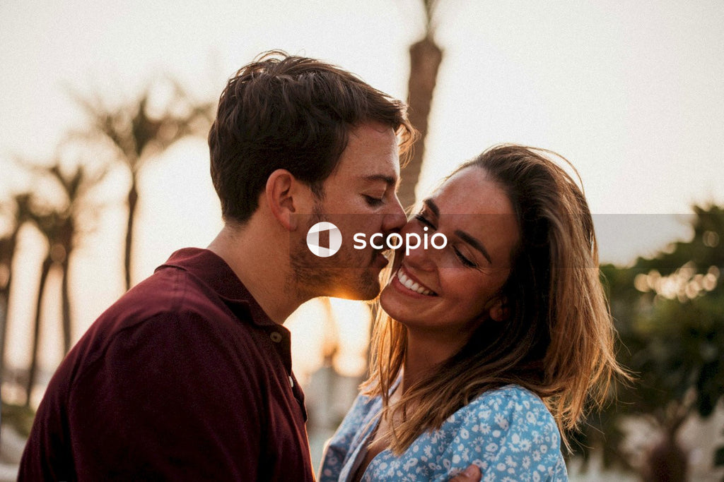 Man in maroon shirt kissing woman in blue and white floral shirt