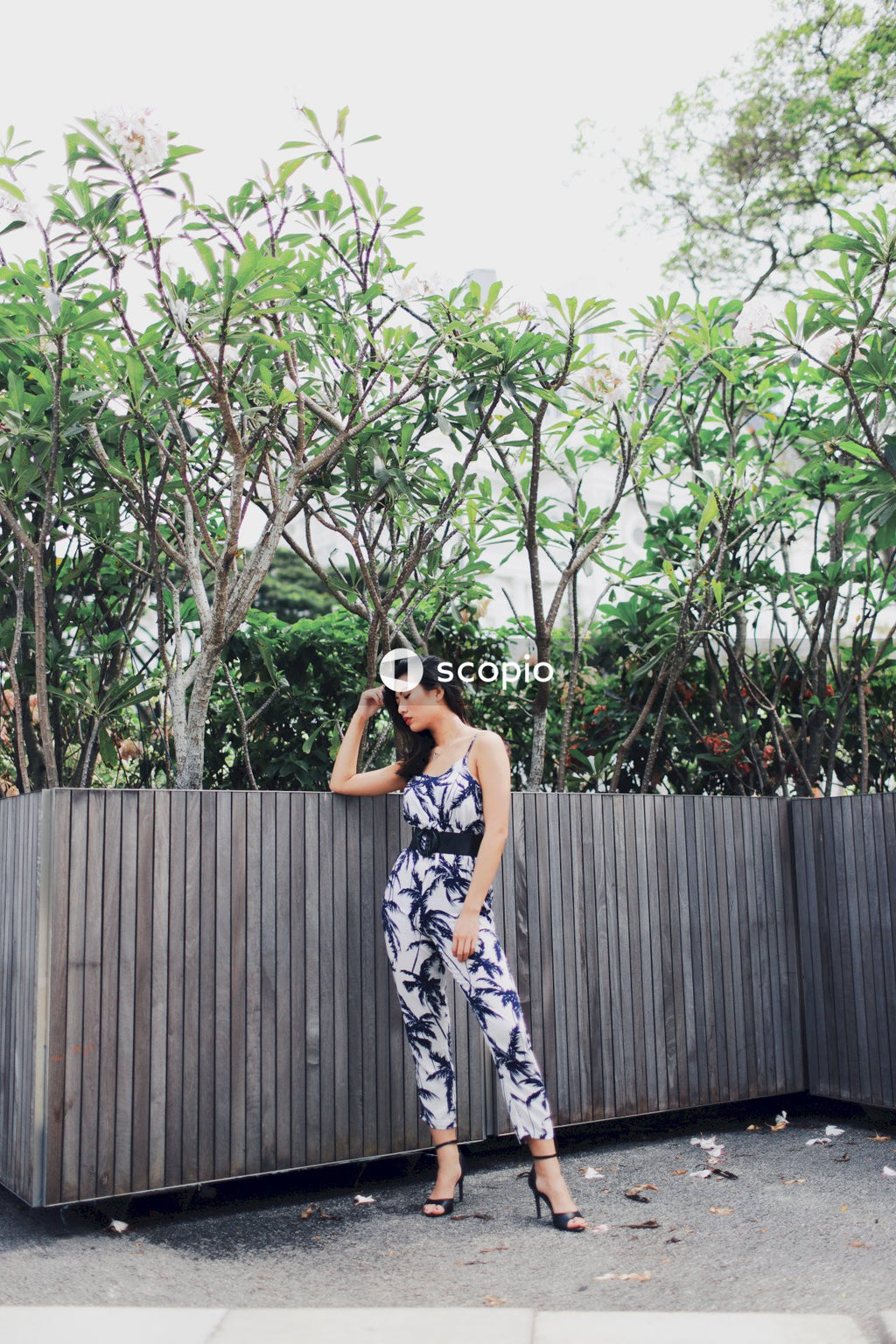 Woman wearing jumpsuit near flower bushes