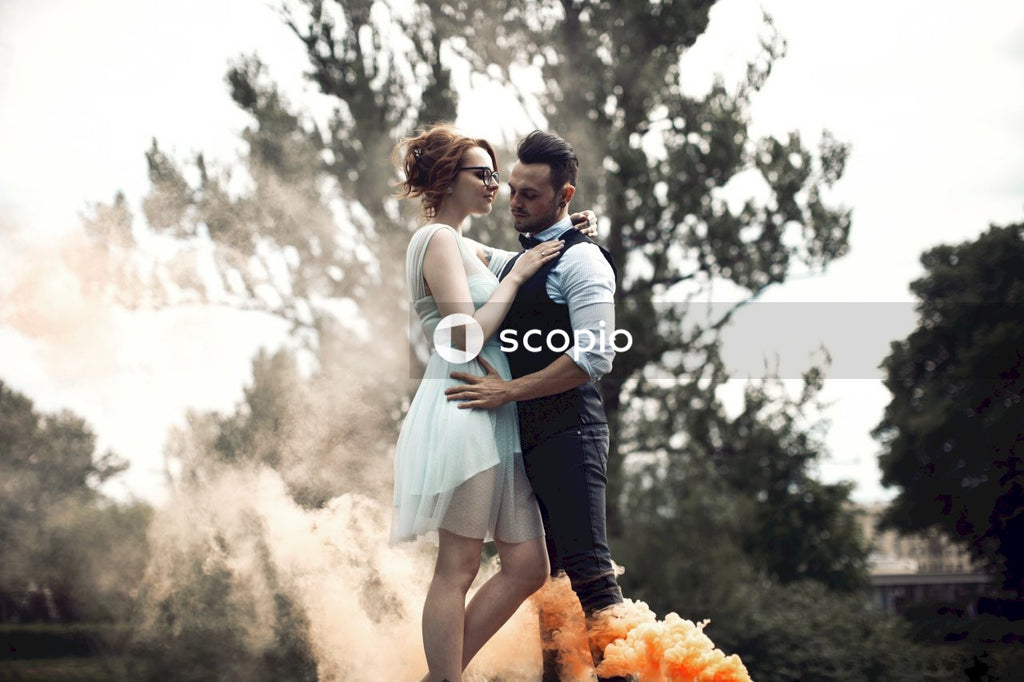 Bride and groom standing beside orange smoke