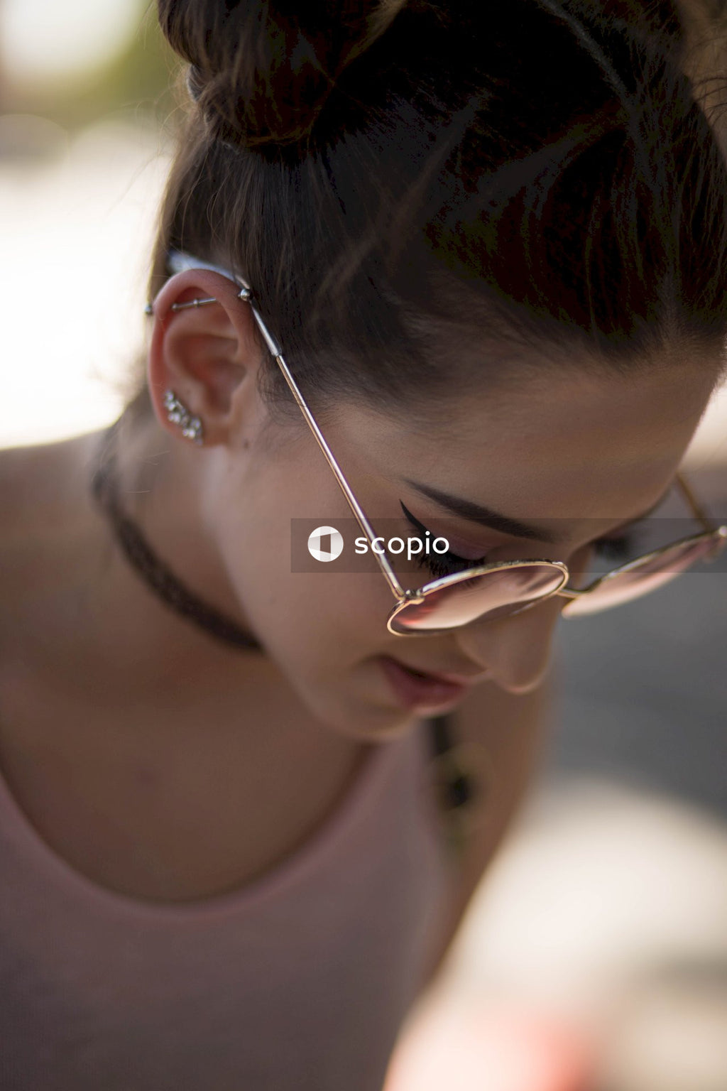 Woman wearing round sunglasses staring down