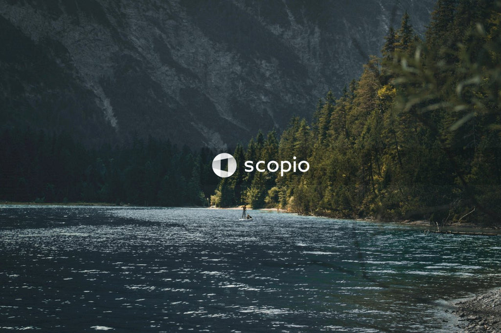 Person riding on white boat on lake near green trees and mountain